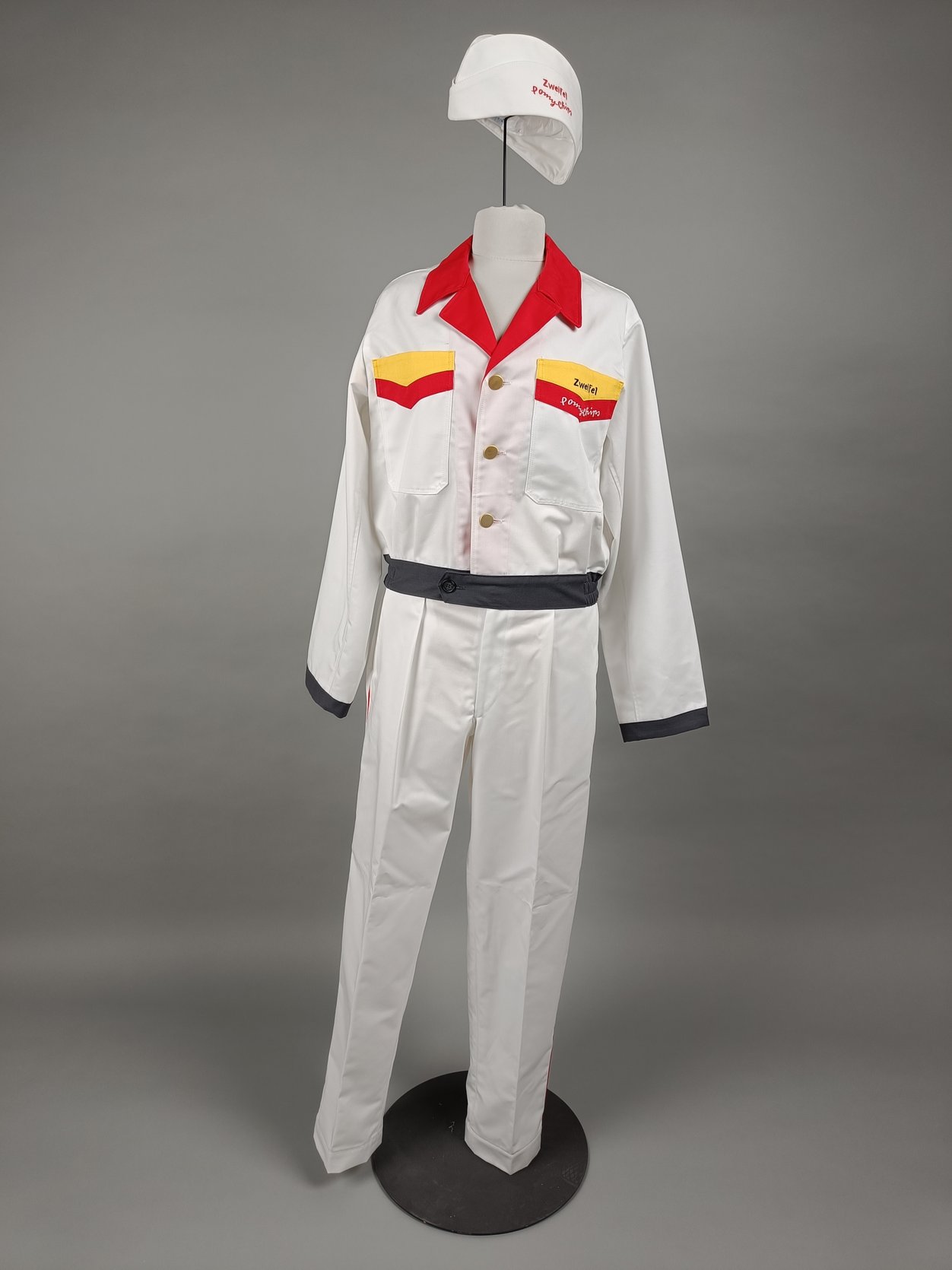 Das Bild zeigt eine Kopie der Frisch-Service-Uniform. Die Kopie ist vorwiegend weiss und weisst an Kragen und Brusttasche rote und gelbe Akzente auf. 