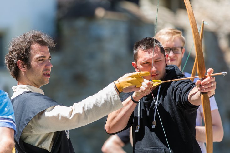 Bogenschiessen Freiwilligenprogramm Museum Aargau: Ein Mann zeigt einem anderen Mann, wie man mit dem Bogen schiesst.