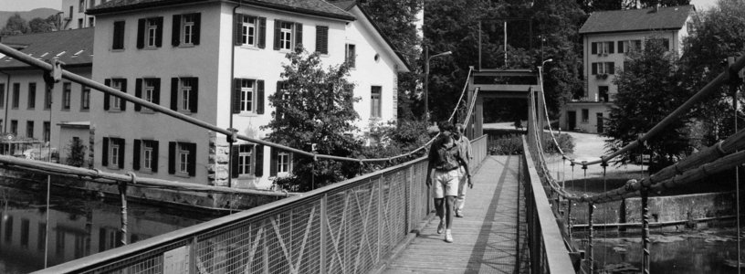 Schwarz-weiss-Aufnahme Spinnerei Wettingen mit Brücke im Vordergrund.
