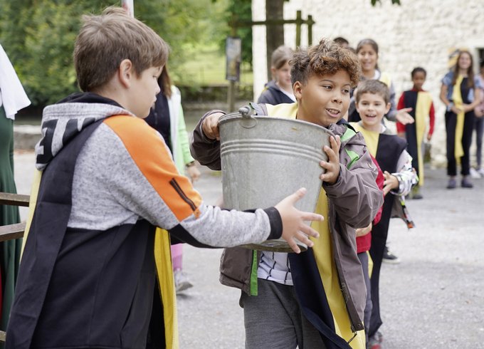 Schüler übergeben sich einen Eimer Wasser und lernen Zusammenarbeit im Workshop für Schulen Schloss Hallwyl