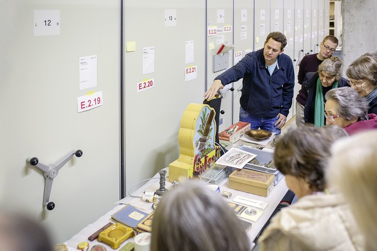 Ein Mann zeigt auf einer Führung im Sammlungszentrum Egliswil historische Objekte aus dem Aargau .