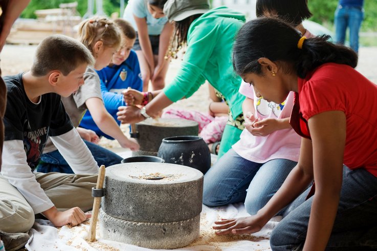  Kinder mahlen Mehl im Workshop auf dem Legionärspfad Vindonissa