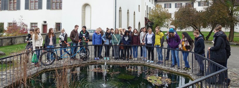 Eine Gruppe Jugendliche steht um einen grossen Brunnen vor dem Kloster Wettingen