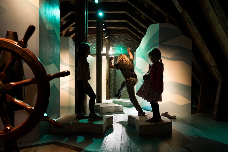 Mystische Aufnahme im Kindermuseum von Schloss Lenzburg: Kinder springen im Gegenlicht von einer Eisscholle auf die nächste.