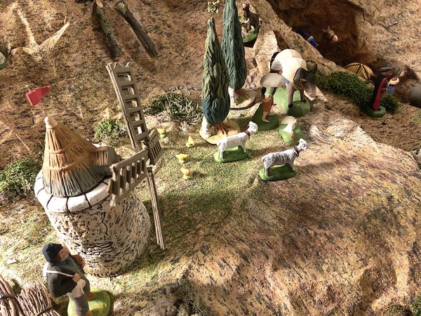 Zu sehen ist eine Szenerie einer provenzalischen Krippe, bei welcher eine Mühle, der Müller, einen Esel beladen mit Mehlsäcken und Ziegen zu sehen sind.
