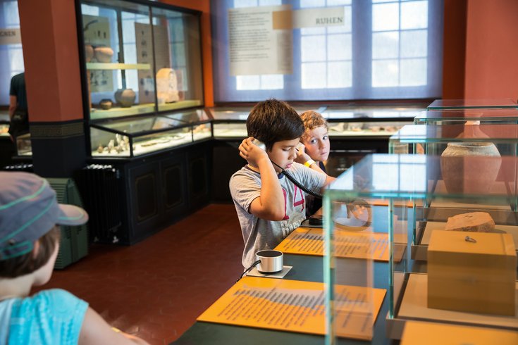 Zwei Jungen betrachten mit Kopfhörern die Dauerausstellung im Vinodnissa Museum