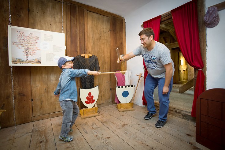 Vater und Sohn spielen in der Kinderstube mit Holzschwertern auf Schloss Wildegg