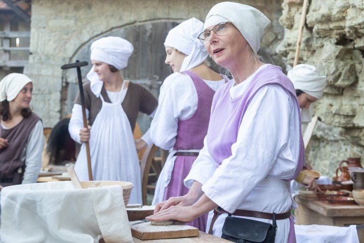 Mehrere historisch gekleidete Frauen, im Hintergrund ein Backofen.