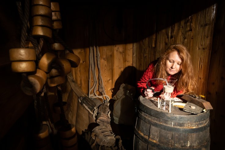 Ausstellung „Blütenduft und Pulverdampf“ auf Schloss Hallwyl: Eine Besucherin riecht an einem Duft-Zerstäuber auf einem hölzernen Fass.