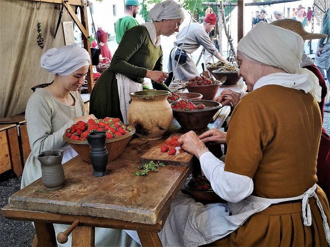 Blick in eine mittelalterliche Küche: Frau rüsten in einem Zelt Gemüse.