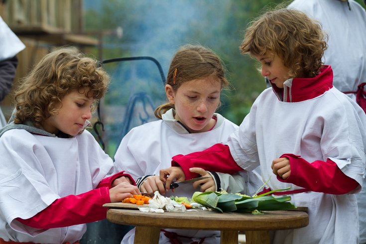 Kinder schneiden Gemüse und Kochen römische Gerichte im Kochworkshop auf dem Legionärspfad 