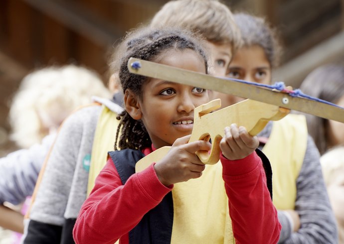 Schülerin visiert in einem Workshop im Schloss Hallwyl ein Ziel mit der Armbrust 