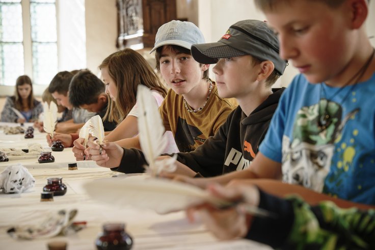 Eine Schulklasse beim Schreiben mit Tinte und Federkiel.