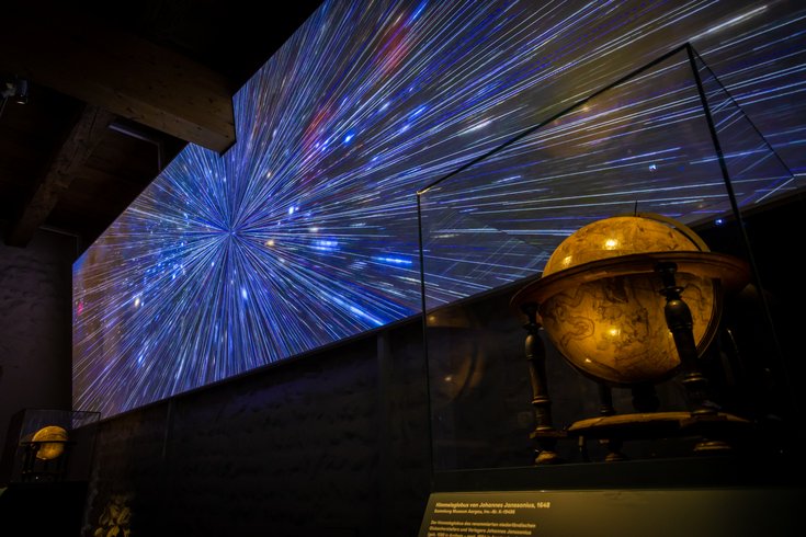 Ausstellung "Observatorium" auf der Klosterhalbinsel Wettingen: Grosse Leinwand mit Sternenhimmel, davor ein grosser historischer Globus.