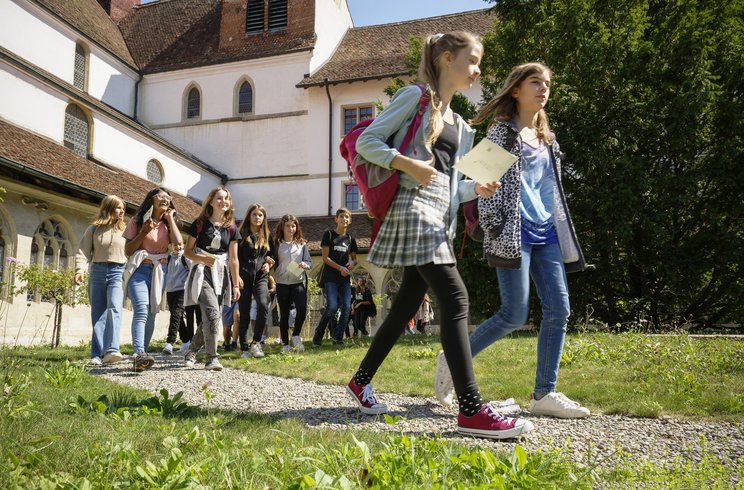 Eine Gruppe Schülerinnen und Schüler schreitet durch den Kreuzganggarten der Klosterhalbinsel Wettingen.