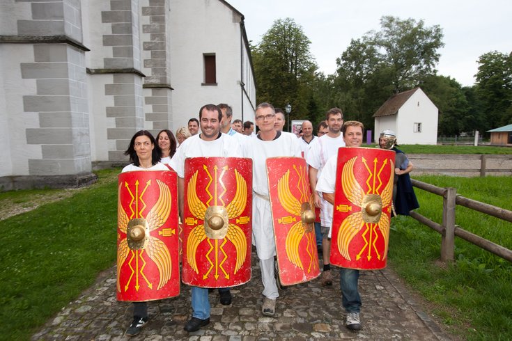 Kinder und Legionäre schreiten verkleidet gewappnet mit Schildern mit der Ausbildung zum Legionär 