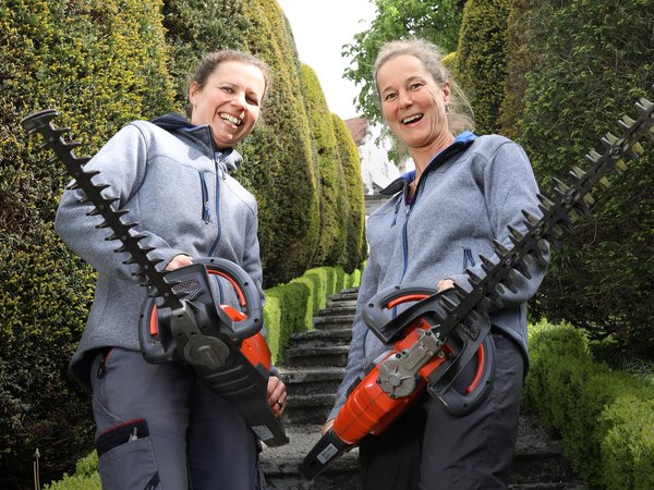 Zwei Frauen stehen mit Kettensägen im Garten von Schloss Wildegg