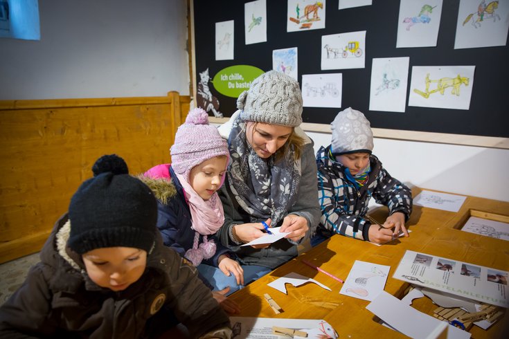 Mutter bastelt mit den Kindern im Pferdestall 