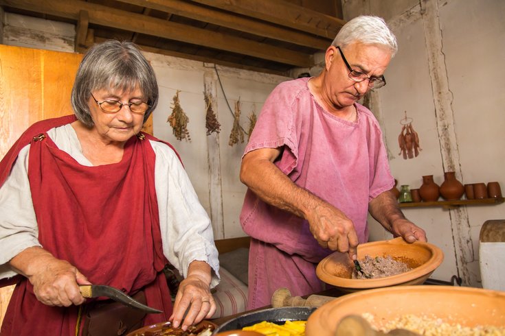 Zwei römisch gekleidete Museumsfreiwillige kochen in einer römischen Küche