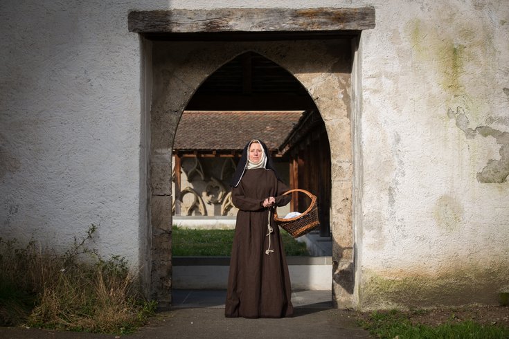 Äbtissin steht mit dem Korb  im Klostertoreingang 