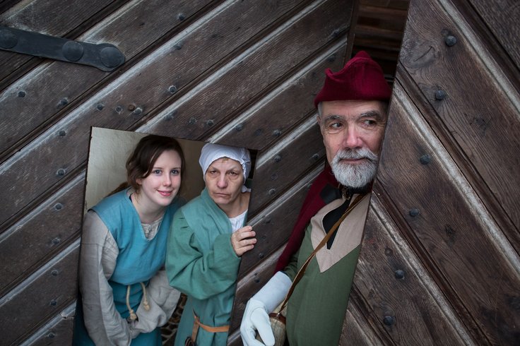 Drei historische gekleidete Personen vor dem Schlosstor.