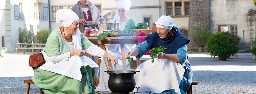 Vier Frauen in historischen Kostümen kochen im Hof von Schloss Lenzburg