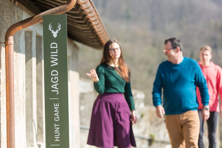 Besucherin und Besucher reden vor dem Eingang der Jagdausstellung auf Schloss Wildegg