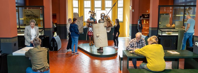 Blick in einen Ausstellungsraum des Vindonissa Museum. Der Raum ist bevölkert mit vielen Besuchenden, in der Mitte zwei lebensgrosse Legionäre.