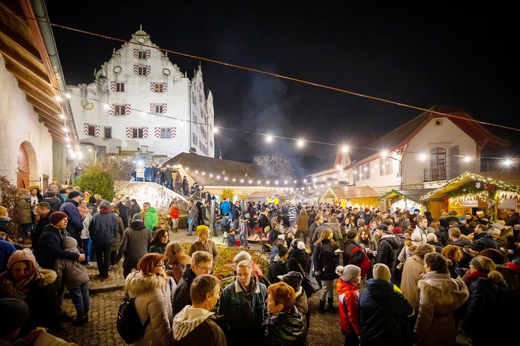 Wiehnachtsmärt Schloss Wildegg: Nachtstimmung mit vielen Menschen im Schlosshof; im Hintergrund das beleuchtete Schloss