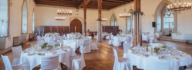 Urige Hochzeitslocation mit weiss gedeckten Tischen im Rittersaal Schloss Lenzburg 