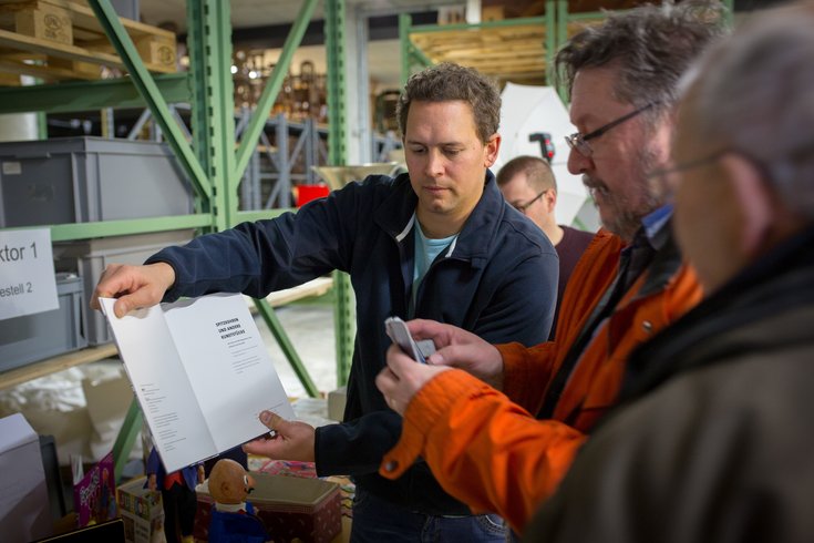 Ein Mitarbeiter zeigt Besuchern ein Buch.
