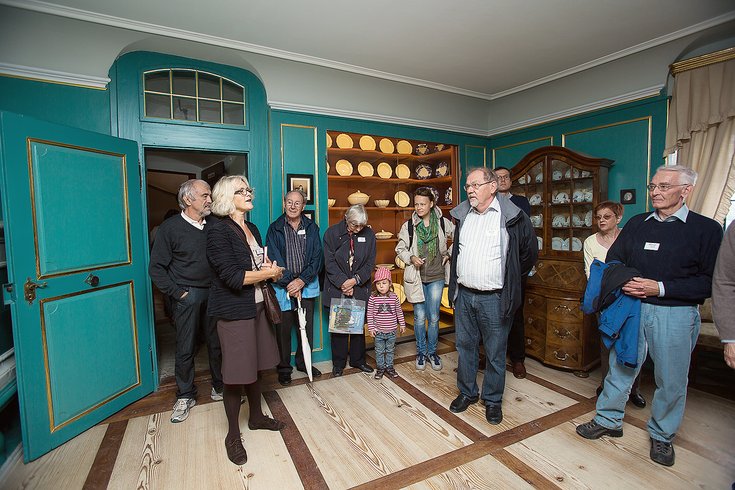 Besucher und Besucherinnen stehen in einem historischen Raum mit smaragdgrünen Wänden auf Schloss Wildegg und sind der Führerin zugewandt