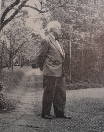 Schwarzweiss Fotografie von Carl Zweifel. Zu sehen ist ein älterer Mann im Anzug auf einer Wiese.